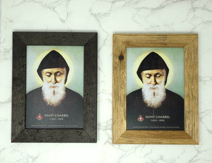 Two framed portraits of Saint Charbel on a marble surface.
